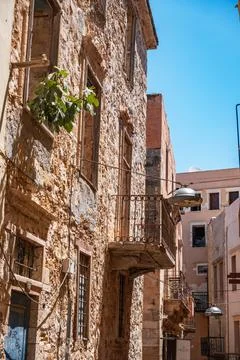 Historic stone building with a rustic balcony on a sunlit street. Stock Photos