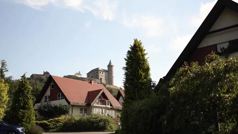 Historic stone castle with a round tower rises above a peaceful village of moder Stock Footage 313843670