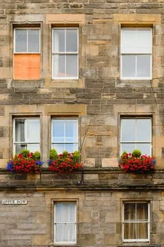 Historic stone facade with shuttered windows and bright flower boxes in city Stock Photos