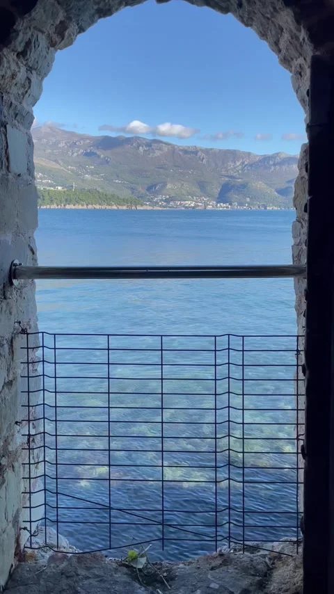 Historic stone gateway overlooking calm waters with scenic landscape and Stock Footage 321500256
