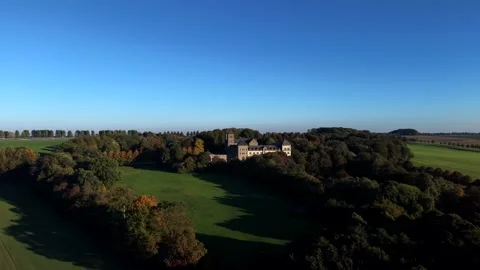 Historic stone monastery rises above dense autumn forest canopy surrounded by Stockbeeldmateriaal 349028997