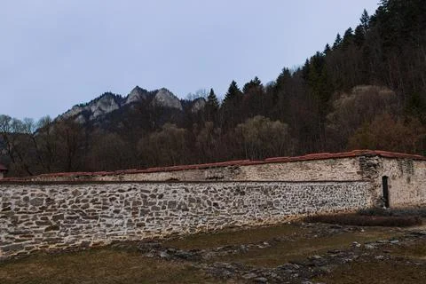 Historic Stone Monastery Wall with Forest and Rocky Mountain Peaks Foto stock