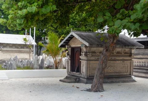 Historic stone structures and ancient graves under a green tree Stock Photos