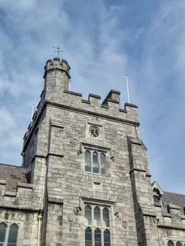 Historic stone tower with clock under dramatic cloudy sky Stock Photos