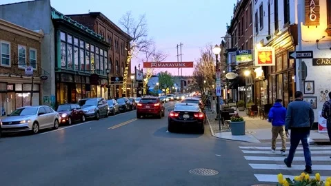 Historic storefronts, banner suspended over Manayunk's Main Street at sunset Vídeo Stock 296206830