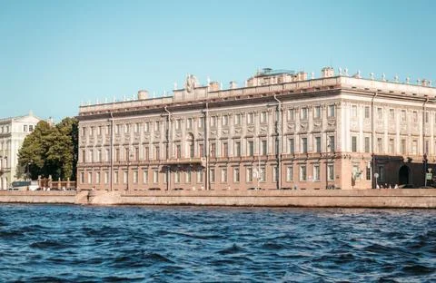 A historic structure sits gracefully by a river under a bright blue sky Stock Photos