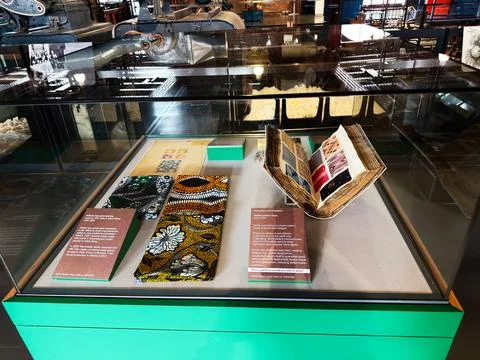 Historic textile pattern samples and open sample book displayed in museum e.. Stock Photos
