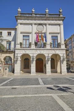 Historic town hall facade with flags in sunny Spanish city square Stock Photos