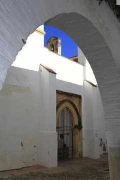 Historic whitewashed arcade framing a bell tower, Andalusia, Spain Stock Photos