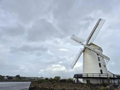 Historic windmill under cloudy sky by the water Stock Photos