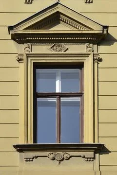 Historic window with triangular pediment on a yellow facade. Fotos de archivo