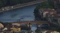 Historical arch bridge connecting two riverbanks at twilight with people walking HD Footage