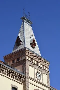 Historical building clock tower with a steep metal roof Stock Photos