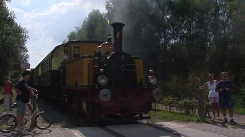 Historical steam train rides towards railway crossing - on camera Stock Footage 32163525