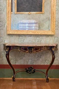 Historical table under the mirror in a gilded frame Stock Photos