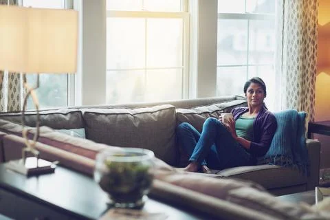 Hit the pause button, have a coffee break. a young woman relaxing on the sofa Stock Photos