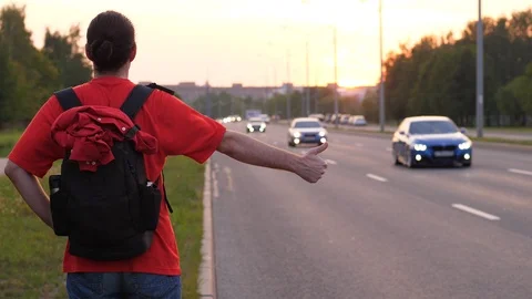 Hitchhiking man stand thumb up on roadside, try to catch car Stock Footage 101828969