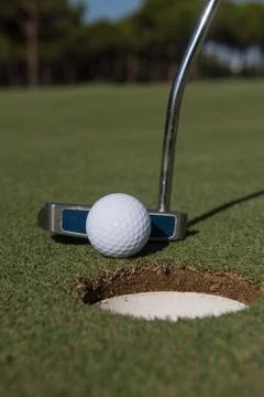 Hitting golf ball to hole 写真素材