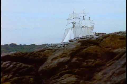 HMS Bounty sails out from behind rocks Stock Footage 86751534