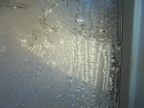 Hoarfrost patterns on window glass, close-up in winter light Stock Photos