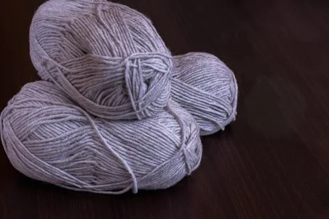 Hobbies and creative activities concept - three skeins of gray yarn on a wood 스톡 사진