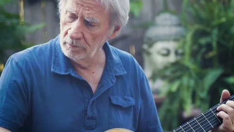 Hobby classical guitar player performing on his acoustic guitar outside tilt up Video stock 78615264