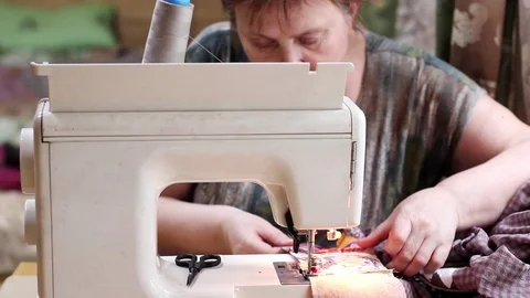 Hobby concept. Grandmother sews patchwork quilt on sewing machine. Front view. Stock Footage 105524824