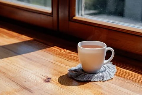 Hobby handmade macrame. Tea in a cup on a gray macrame stand on a wooden wind Foto stock