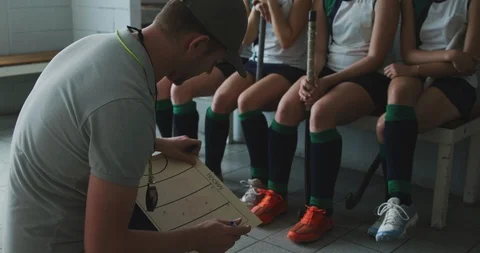 Hockey coach explaining game plan with female players in locker room Stock-Footage 124591696