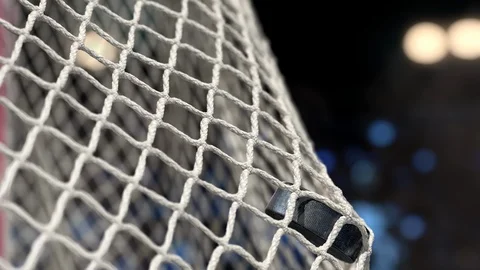 Hockey puck flies into the net on a stadium with yellow and blue lights. Stock Footage