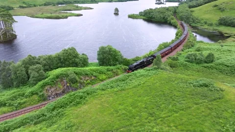 Hogwarts Express train is traveling down a track next to a body of water Stock Footage 306560348