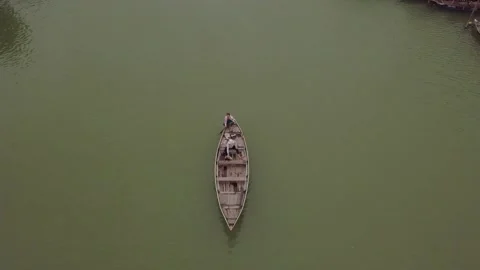 Hoi An river surface man rows boat and friend bails water Stock Footage 159857709