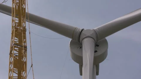 Hoisting and fitting a blade wind turbine to nacelle - medium shot Stock Footage 245363038