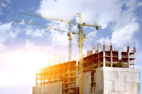 Hoisting cranes working building construction on bright blue sky and big cl.. Stock Photos