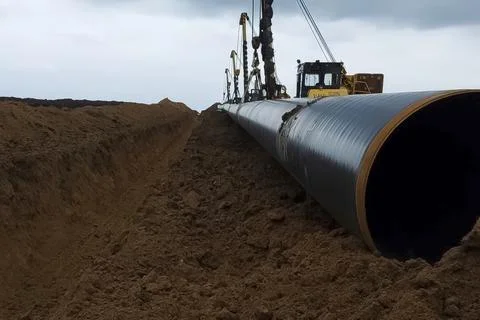 Hoists synchronously move installed pipeline into the trench dug for it. In.. Stock Photos