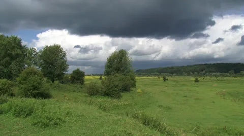 Hold + pan - Dark clouds above Dutch river landscape + moraine hill Stock Footage 23766613