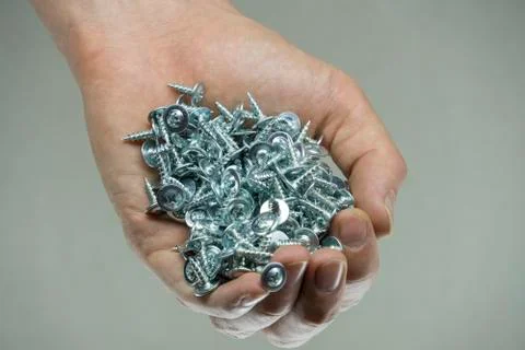 Hold a set of cogs in your hand. Bolts in a man's hand. Screws and cogs. Tool Stock Photos