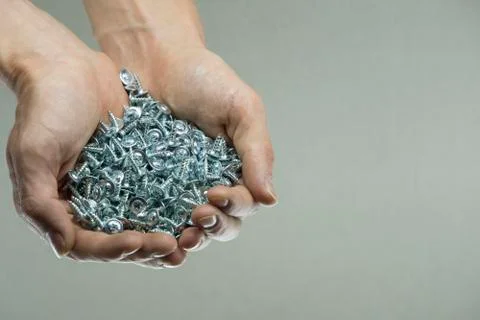 Hold a set of cogs in your hands. Bolts in a man's hands. Screws and cogs. To 스톡 사진