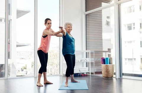 Hold your arms a bit higher up. a fitness instructor helping a senior woman 스톡 사진
