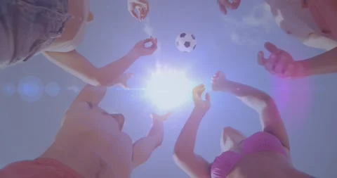 Holder lifting and tossing soccer ball for beach sport, group reaching into sun Stock Footage 329908989