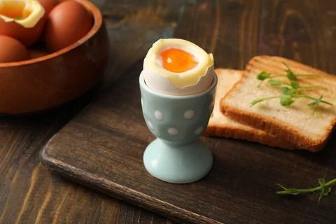 Holder with soft boiled egg, micro green and slices of bread on wooden backgr Stock Photos