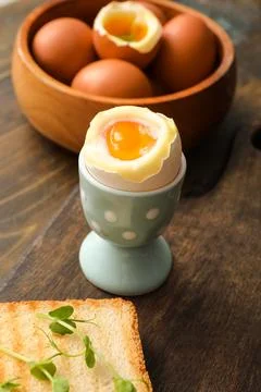 Holder with soft boiled egg, micro green and slice of bread on wooden backgro Stock Photos