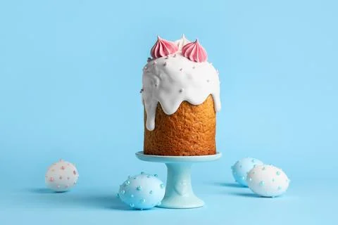 Holder with sweet Easter cake and painted eggs on blue background Stock Photos