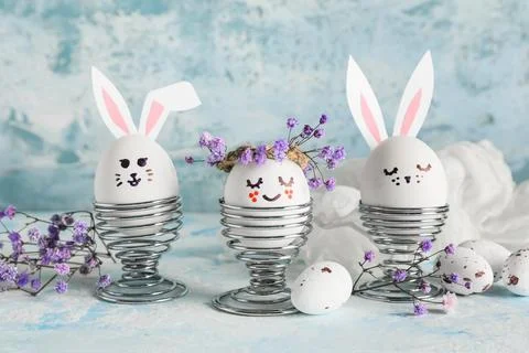Holders of creative Easter eggs with flowers on grunge blue background Stock Photos