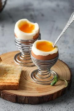 Holders with soft boiled eggs and bread slice on grey background Stock Photos