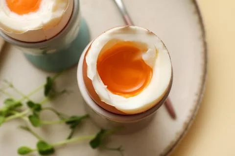 Holders with soft boiled eggs and micro green on light background, closeup Stock Photos