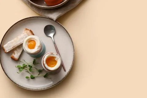 Holders with soft boiled eggs, micro green and pieces of bread on light backg Stock Photos