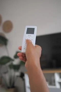 Holding a air condition remote control in a living room setting Stockfoto's