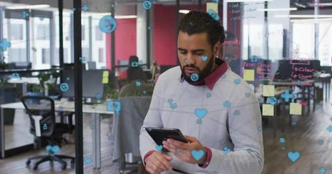 Holding and using tablet man in gray sweater at office, glass partition with Foto stock