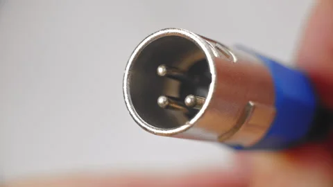 Holding blue and silver, audio, XLR sound cable plug in fingers Stock Footage 286121437